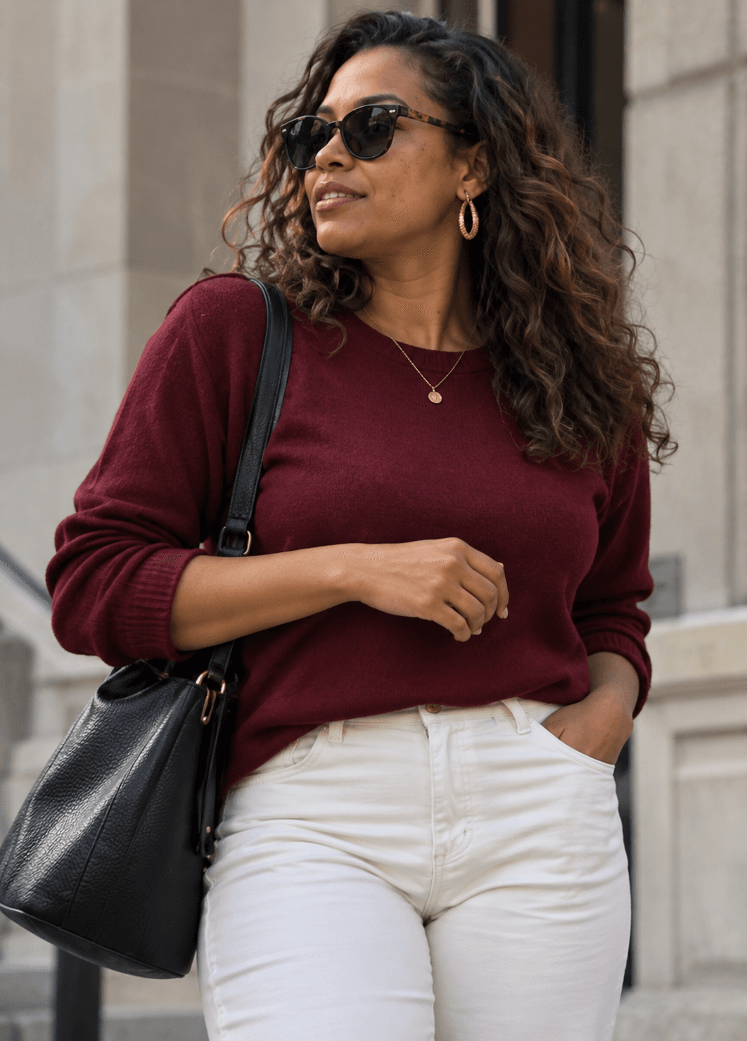 A woman in an urban chic outfit standing by a stone entrance.